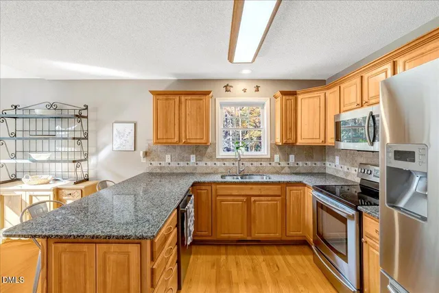a kitchen with stainless steel appliances granite countertop a sink stove and cabinets