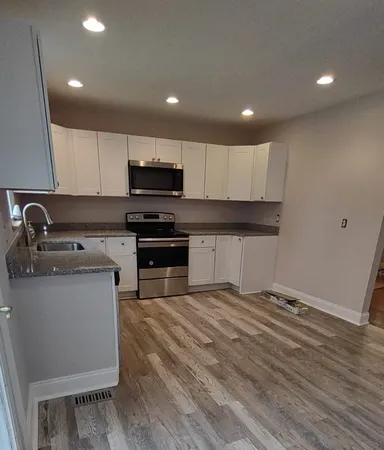 a kitchen with sink a microwave and cabinets