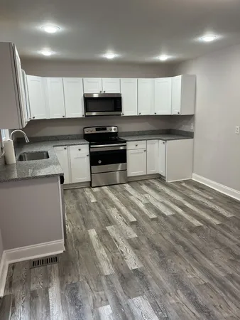 a kitchen with granite countertop a stove a sink and a microwave