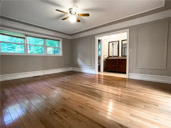 a view of empty room with wooden floor and fan