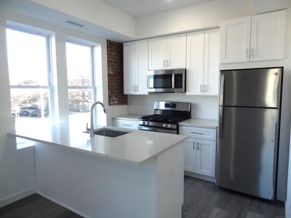 a kitchen with stainless steel appliances a refrigerator a sink a stove a microwave and cabinets