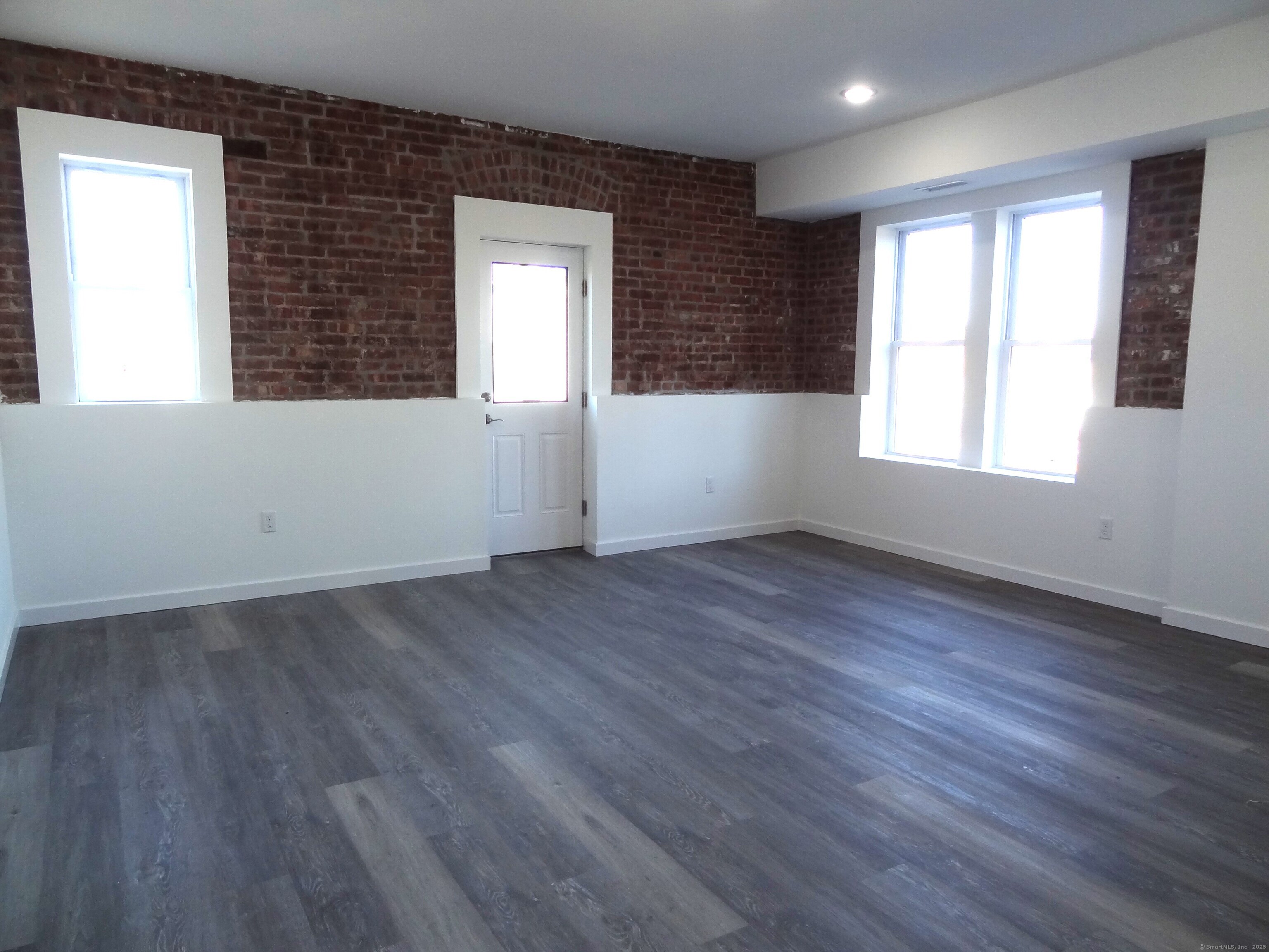 2806 Fairfield Avenue, Unit 101 Bridgeport, CT 06605 - Photo 6 of 25 an empty room with wooden floor and windows