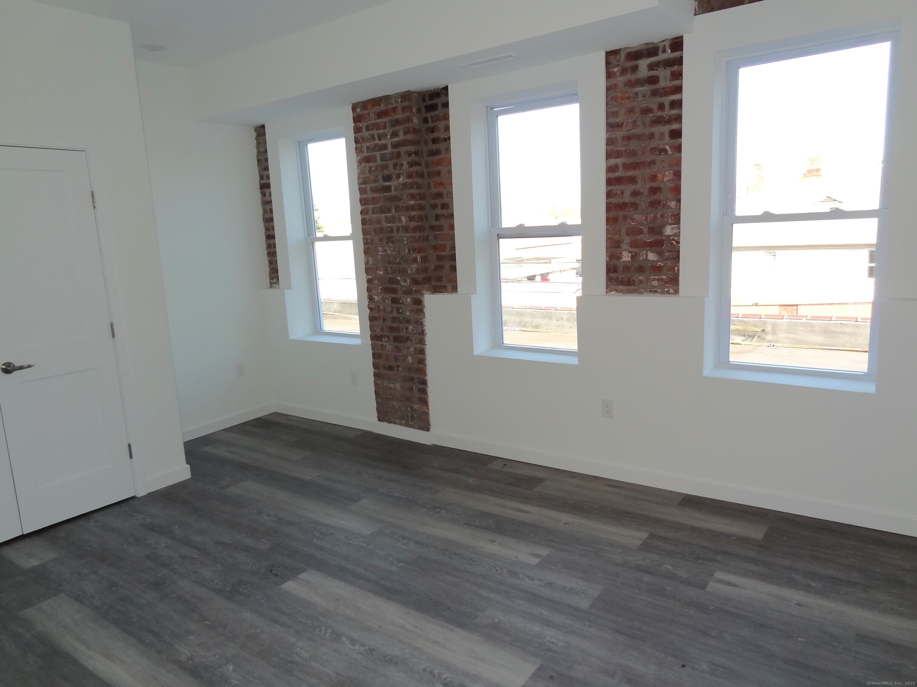 2806 Fairfield Avenue, Unit 101 Bridgeport, CT 06605 - Photo 9 of 25 an empty room with wooden floor and windows