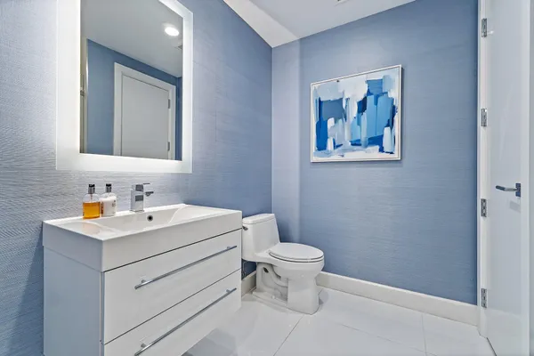 a bathroom with a toilet a sink a mirror and vanity