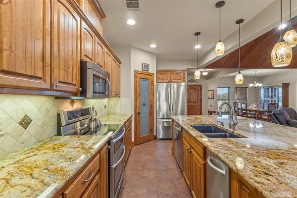 a kitchen with stainless steel appliances granite countertop a sink a stove and a refrigerator