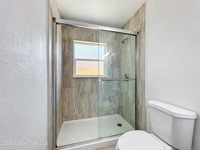 a bathroom with a shower a toilet and a window