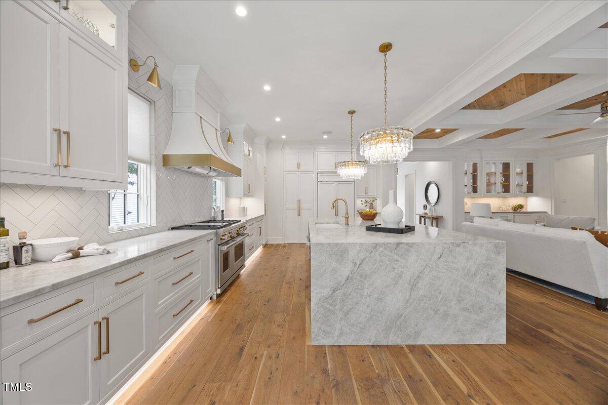 a large kitchen with kitchen island a stove a sink a center island and wooden floor