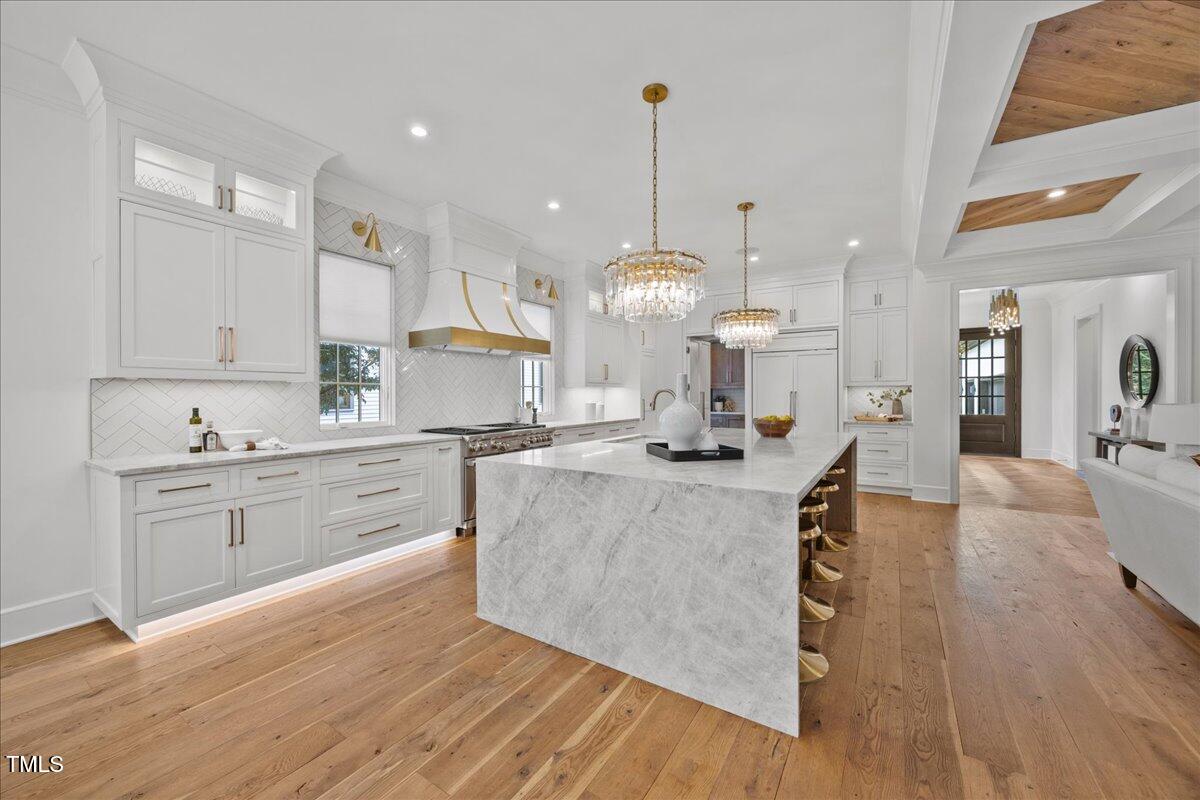 2120 Kipawa Street Raleigh, NC 27607 - Photo 17 of 77 a large kitchen with stainless steel appliances kitchen island granite countertop a stove a sink a refrigerator and white cabinets with wooden floor