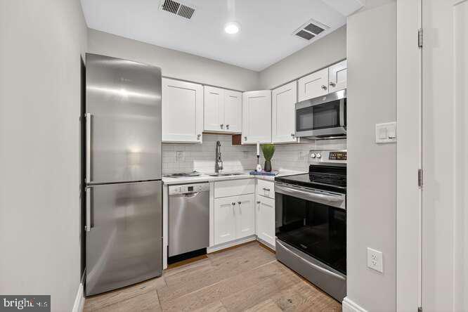 1450 Fairmont Street Northwest, Unit A Washington, DC 20009 - Photo 8 of 14 a kitchen with cabinets stainless steel appliances and a counter space