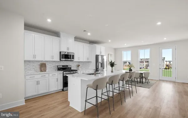 a kitchen with stainless steel appliances a dining table chairs stove and white cabinets