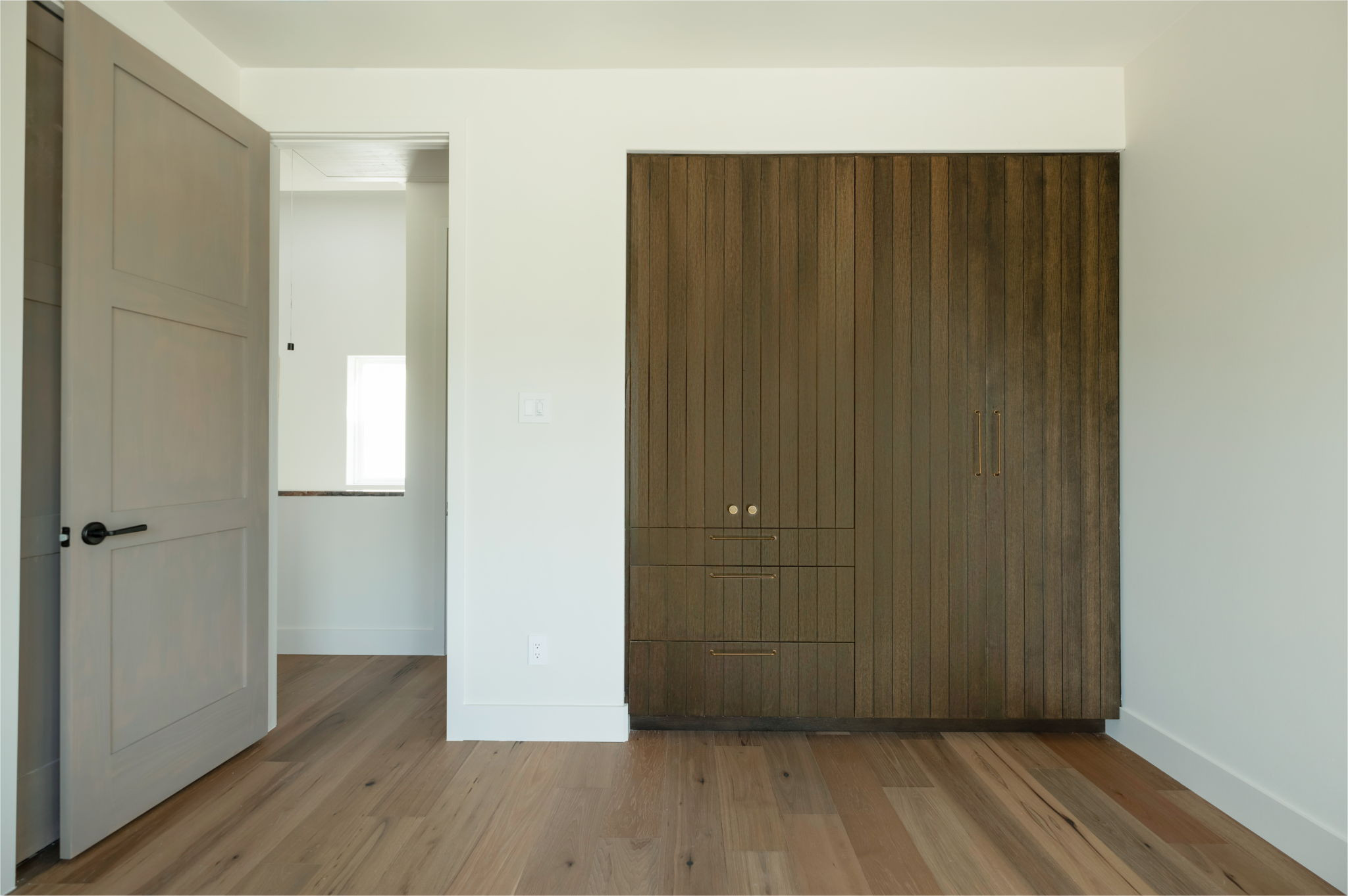 4713 Bolm Road Austin, TX 78702 - Photo 32 of 40 Integrated wood-finish cabinetry with recessed hardware, complemented by light wood-finish flooring and a contemporary interior door with matte black hardware
