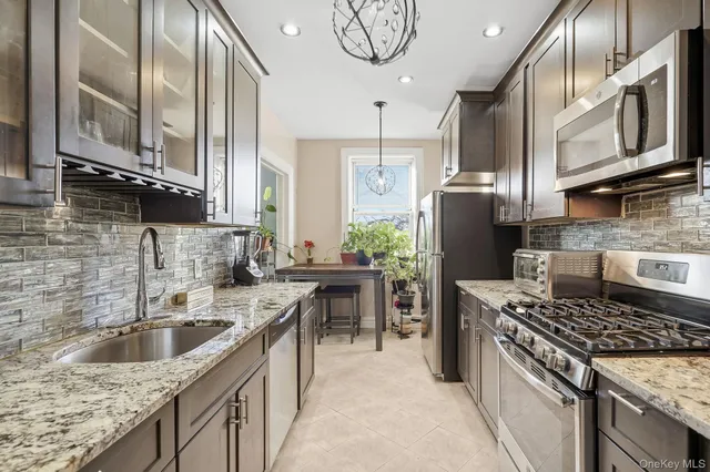 a kitchen with stainless steel appliances granite countertop wooden cabinets a stove top oven a sink and dishwasher