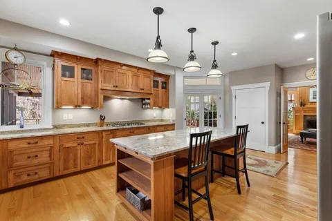 a kitchen with granite countertop a stove a sink a dining table and chairs with wooden floor