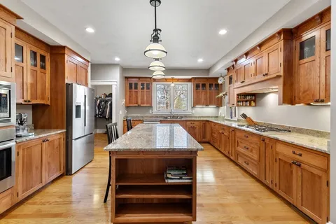 a large kitchen with stainless steel appliances granite countertop plenty wooden cabinets counter space a sink and a center island