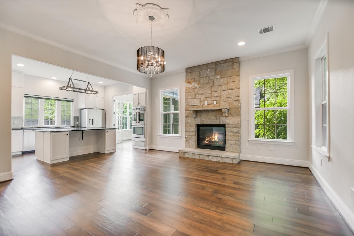 5200 Avenue H Austin, TX 78751 - Photo 13 of 20 an empty room with wooden floor a fireplace a chandelier and windows