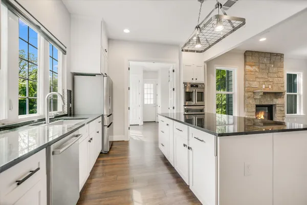 a large kitchen with granite countertop a large counter top space a sink stainless steel appliances and cabinets