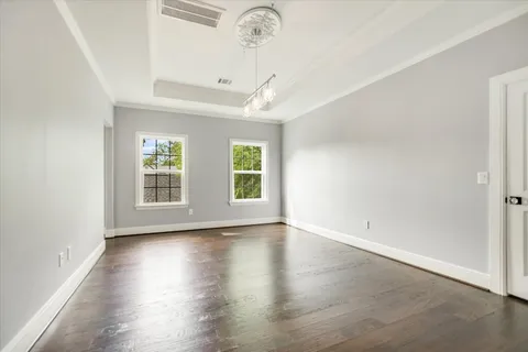an empty room with wooden floor chandelier and windows