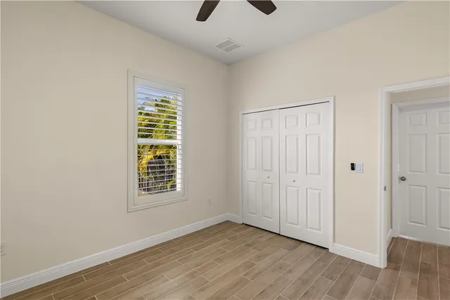 an empty room with wooden floor cabinet and windows