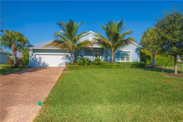 a view of a white house with a big yard and palm trees