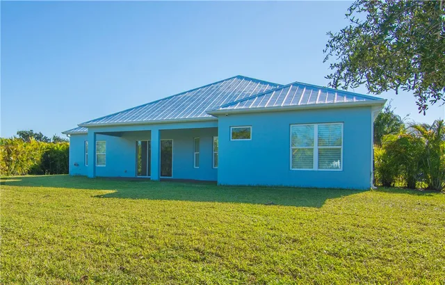 a view of a house with a yard and potted plants