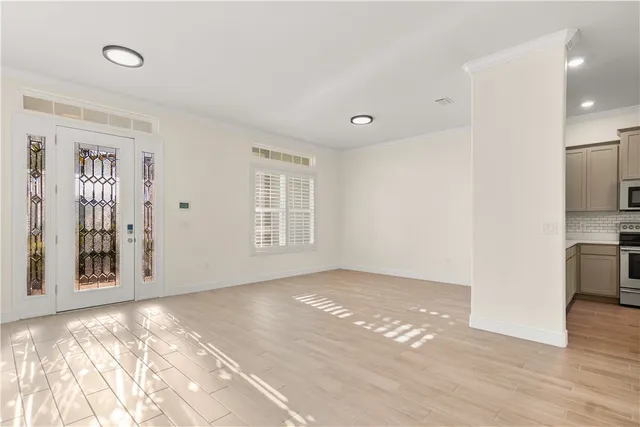 a view of an empty room with window and wooden floor