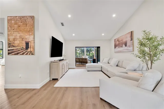 a living room with furniture a flat screen tv and a floor to ceiling window