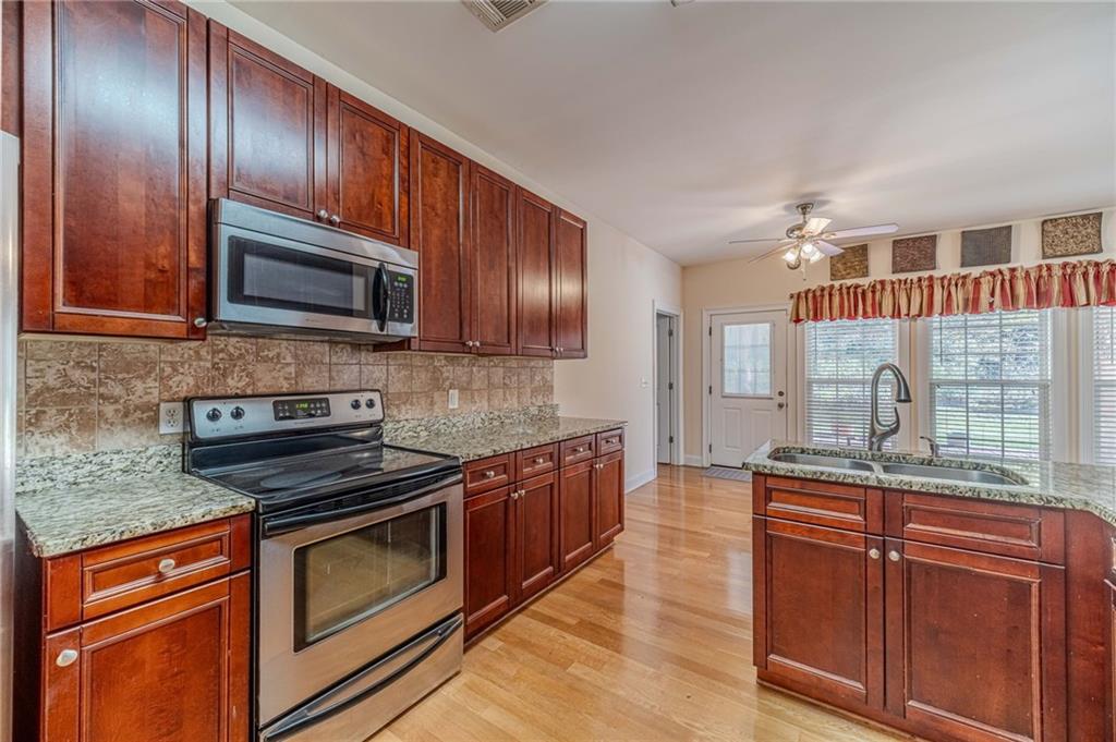 654 Huntington Trace Winder, GA 30680 - Photo 13 of 51 a kitchen with granite countertop wooden cabinets stainless steel appliances and a sink