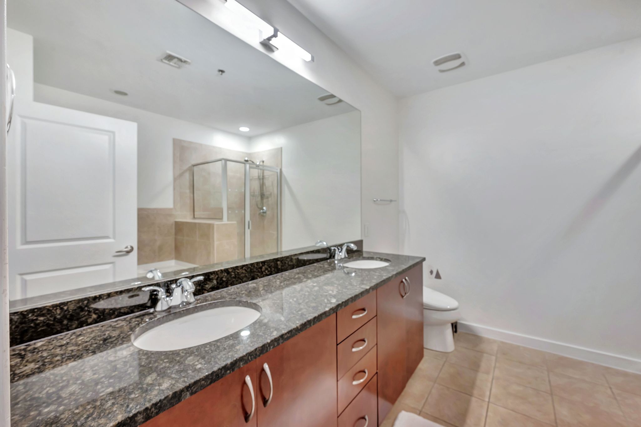 301 Demonbreun Street, Unit 1120 Nashville, TN 37201 - Photo 19 of 51 a bathroom with a granite countertop double vanity sink and a mirror
