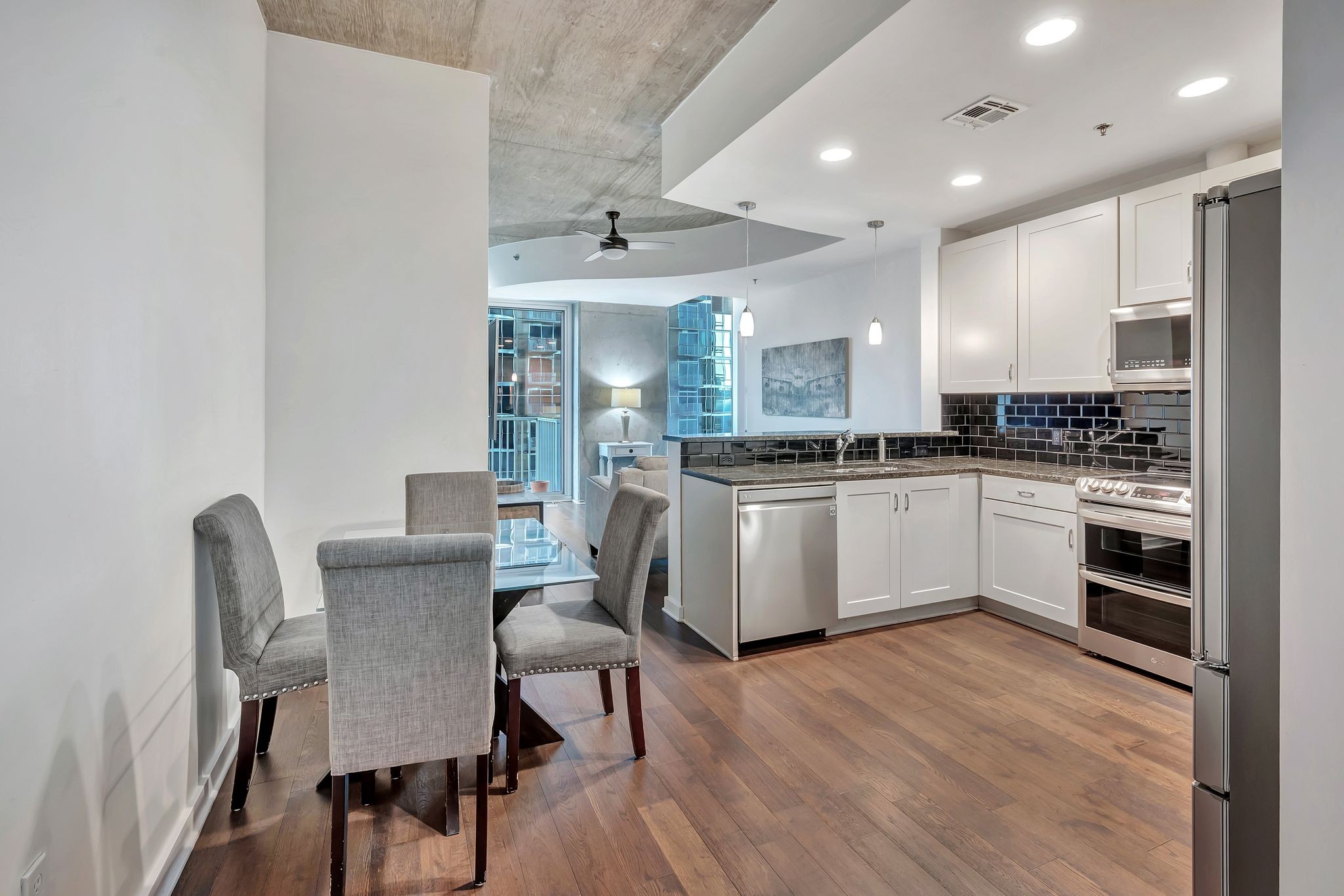 301 Demonbreun Street, Unit 1120 Nashville, TN 37201 - Photo 6 of 51 a kitchen with a table chairs a sink a stove a microwave and cabinets