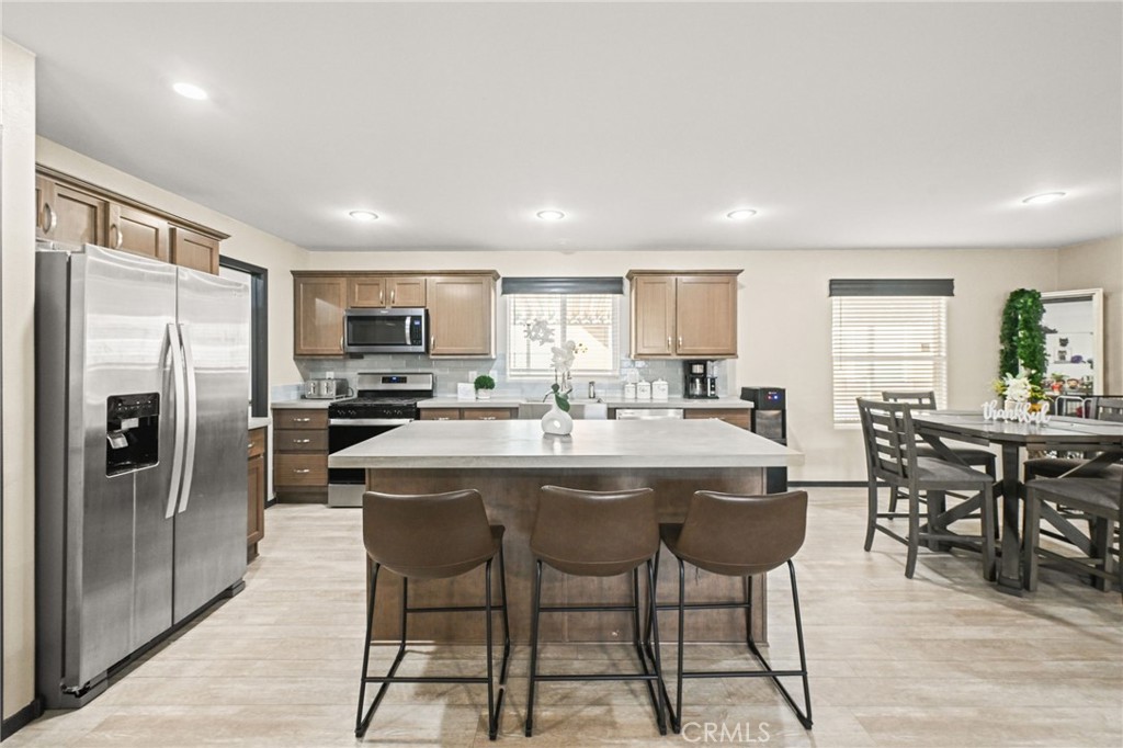 16860 Slover Avenue, Unit 70 Fontana, CA 92337 - Photo 8 of 38 a kitchen with stainless steel appliances a dining table chairs refrigerator and cabinets