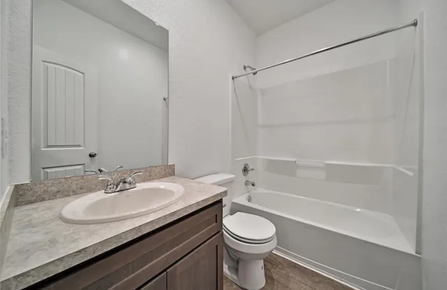 a bathroom with a granite countertop sink a toilet and shower