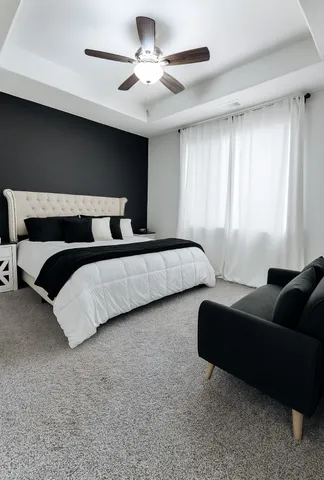 a bedroom with a bed couch chandelier and a window
