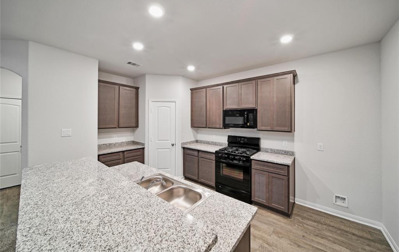 14224 Grand Hills Drive Conroe, TX 77303 - Photo 9 of 17 a kitchen with stainless steel appliances granite countertop a stove sink and cabinets
