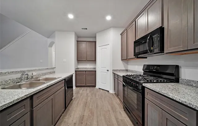 a kitchen with stainless steel appliances granite countertop a sink stove microwave and cabinets