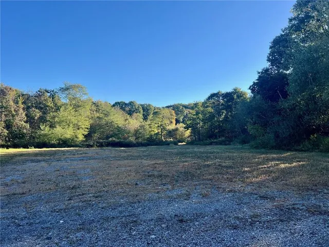 a view of dirt field with trees in background