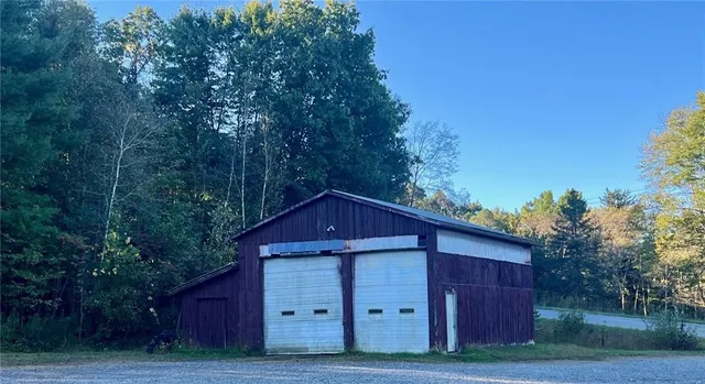 a view of a barn in a big yard with large trees