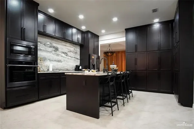 a kitchen with stainless steel appliances kitchen island granite countertop a refrigerator and a wooden cabinets