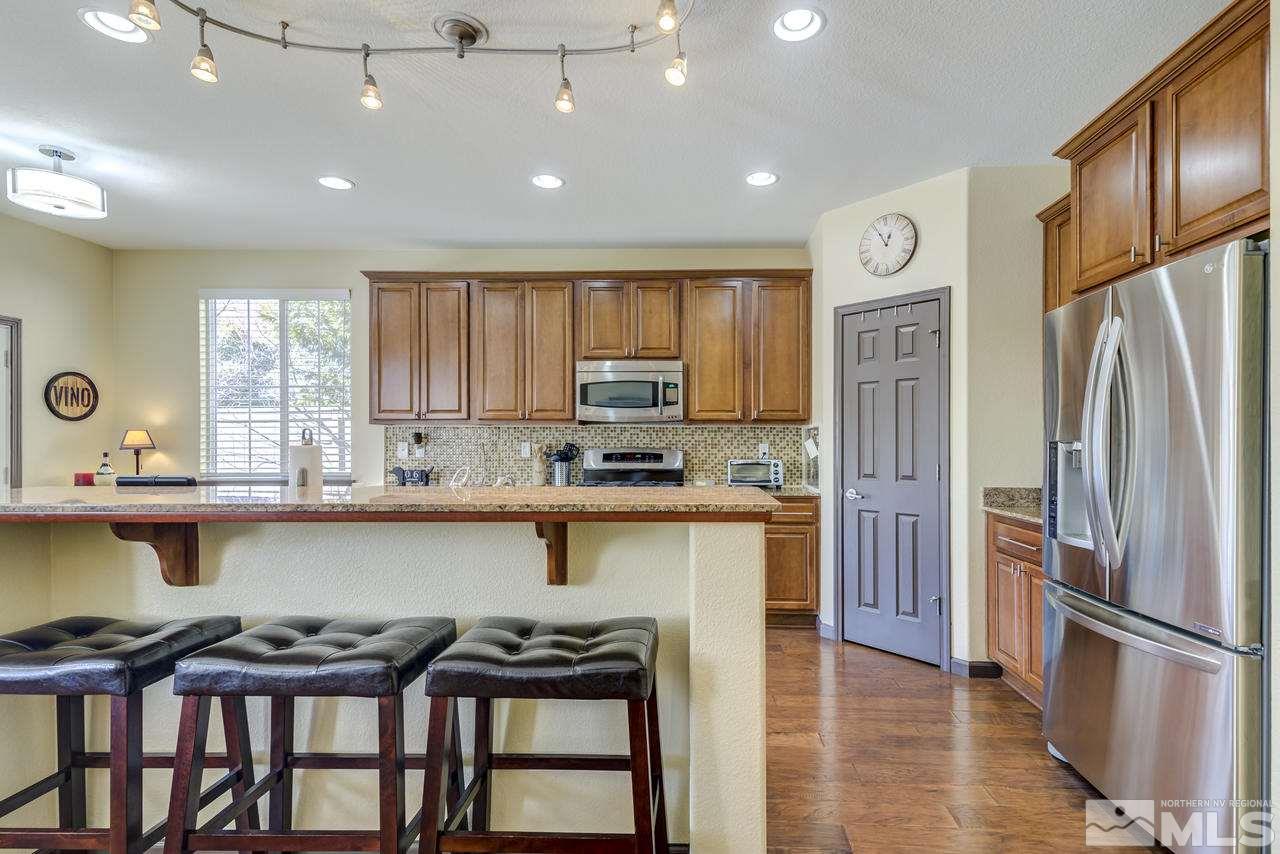 460 Ruffian Court Reno, NV 89521 - Photo 8 of 25 a kitchen with stainless steel appliances granite countertop a refrigerator a stove a sink dishwasher and a microwave with wooden floor