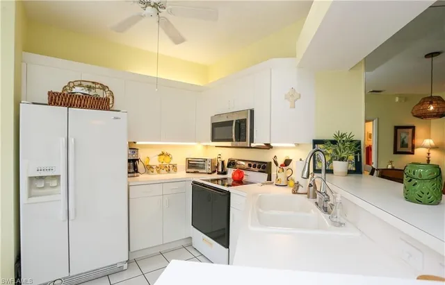 a kitchen view with stainless steel appliances a stove a refrigerator a sink dishwasher with a dining table and chairs