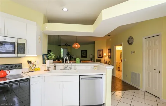 a hall with kitchen island a sink stainless steel appliances and cabinets
