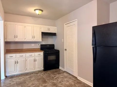 a kitchen with granite countertop white cabinets and refrigerator