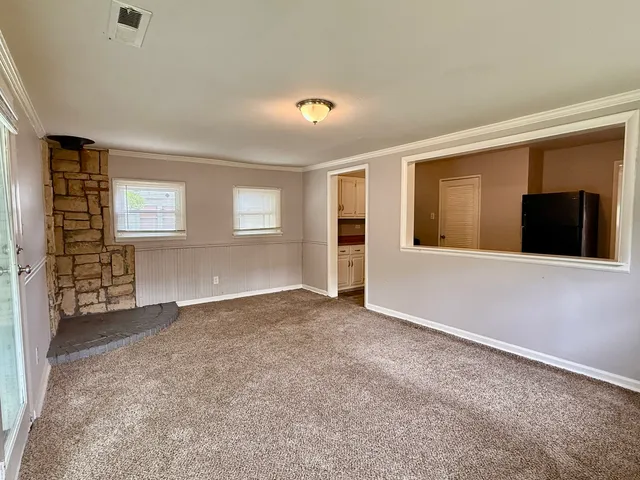 a view of an empty room with a window and fireplace