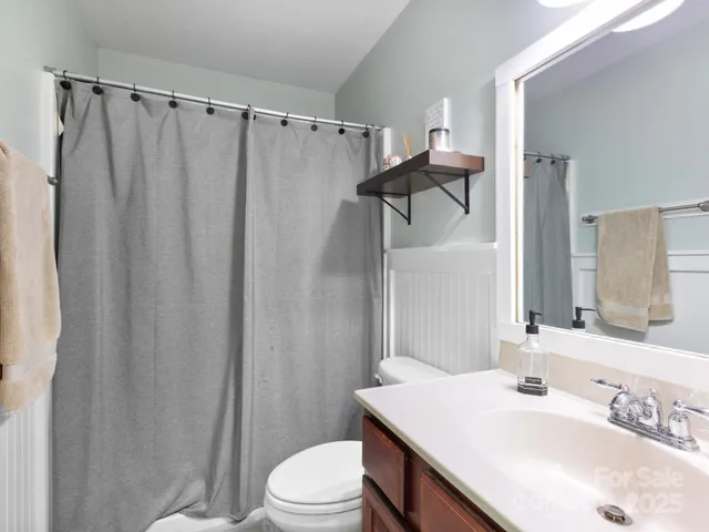 a bathroom with a sink a toilet a mirror and shower curtain