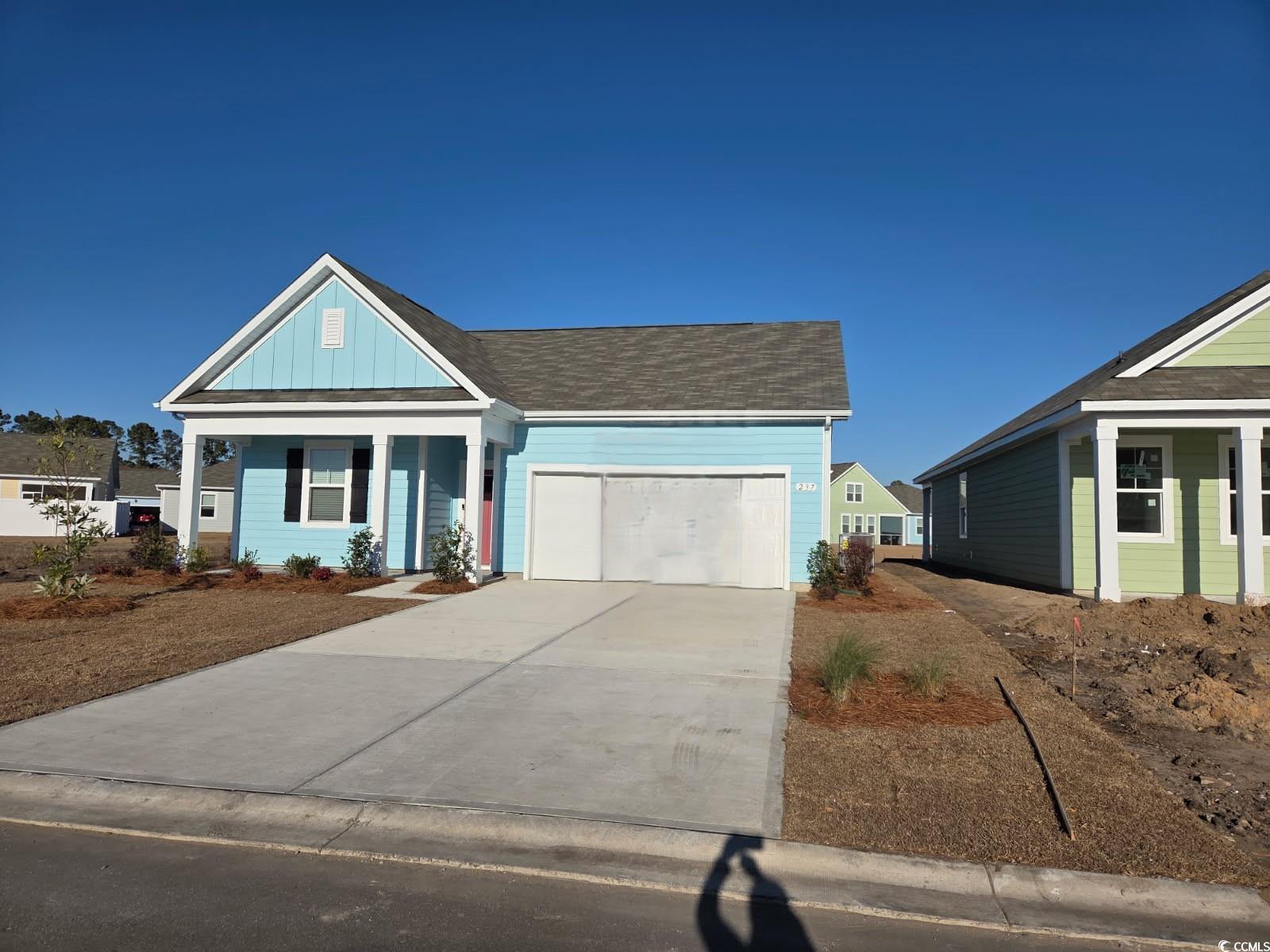 View of front of home featuring a porch, concrete driveway, a garage, board and batten siding, and roof with shingles