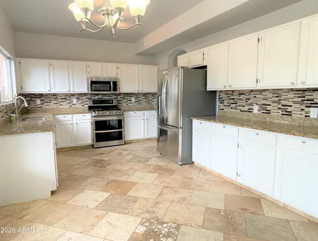 a kitchen with stainless steel appliances granite countertop a stove a sink and a refrigerator