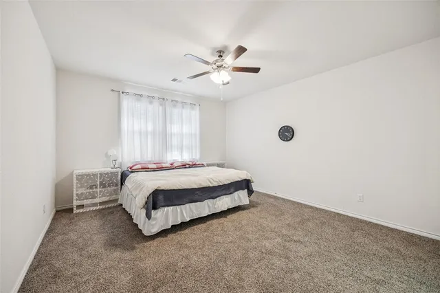 a spacious bedroom with a bed and a ceiling fan