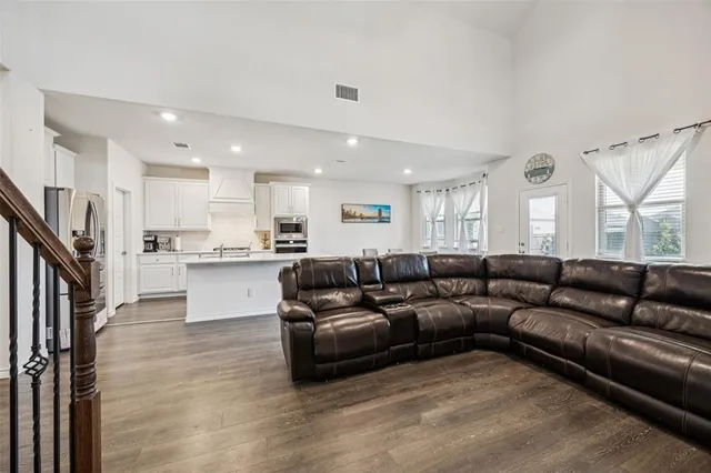 a living room with couches and kitchen view with wooden floor