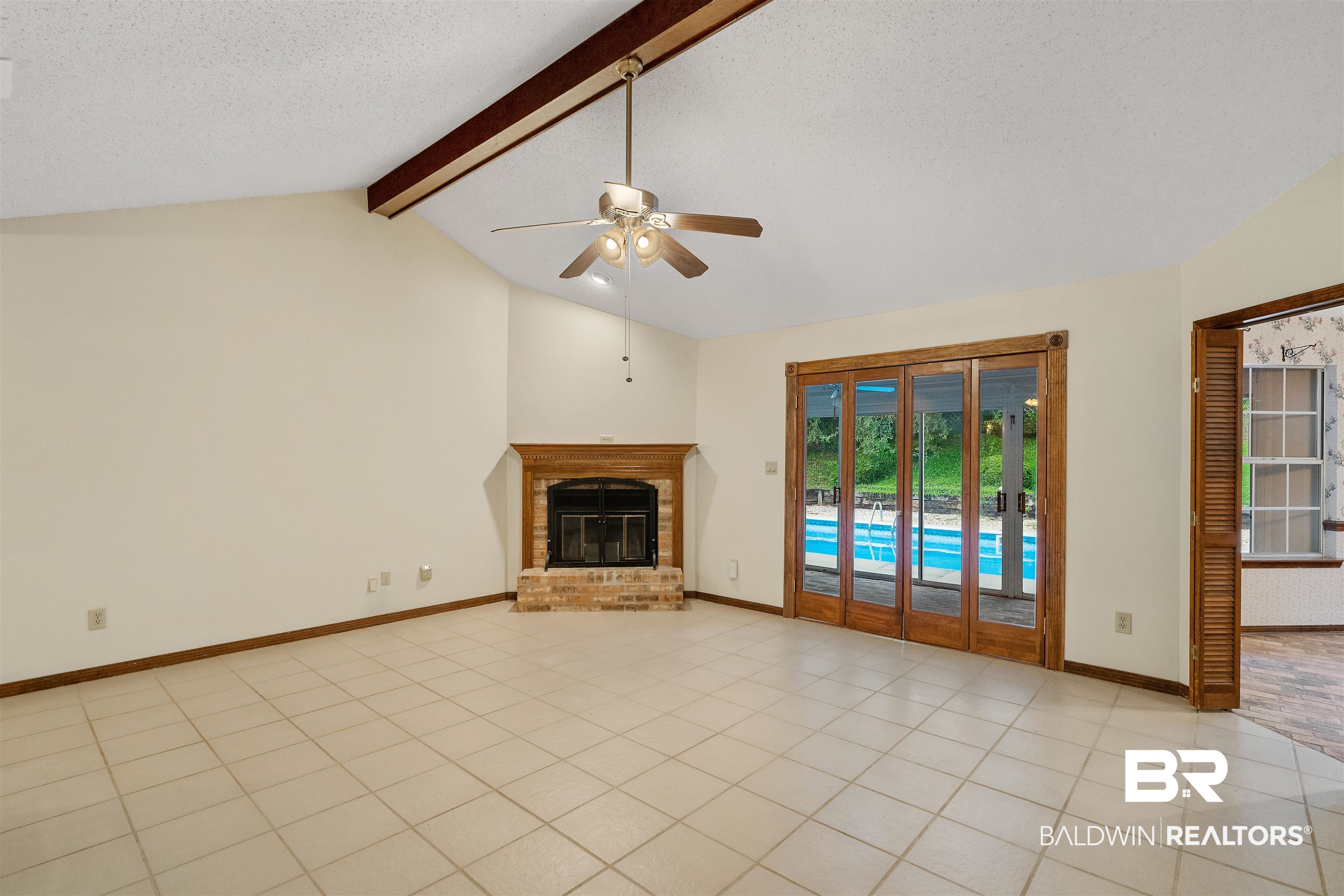 438 Ridgewood Drive Daphne, AL 36526 - Photo 7 of 28 Unfurnished living room with lofted ceiling with beams, a textured ceiling, a fireplace, light tile patterned floors, and ceiling fan