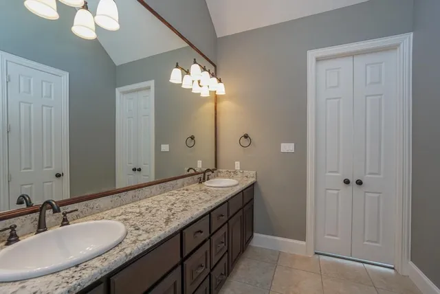a bathroom with a granite countertop double vanity sink and a mirror
