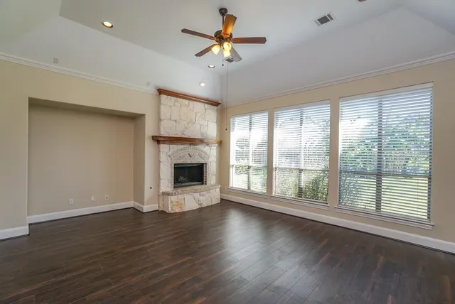 a view of a livingroom with a fireplace a ceiling fan and wooden floor